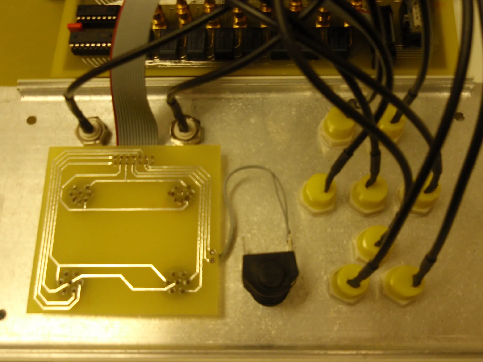 Inside the switch: a hand-etched board with wide traces, a bank of relays and gold-plated jack sockets above it on a ribbon cable, and the yellow panel sockets with their leads